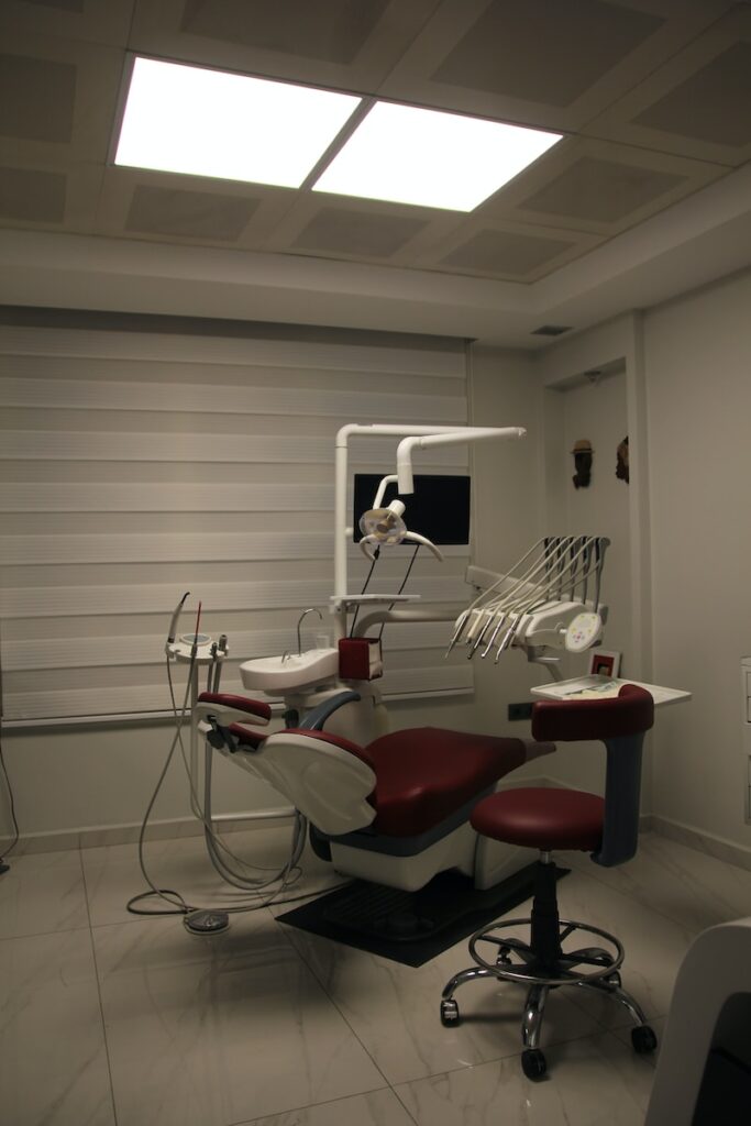 a dentist chair with a red seat in a room